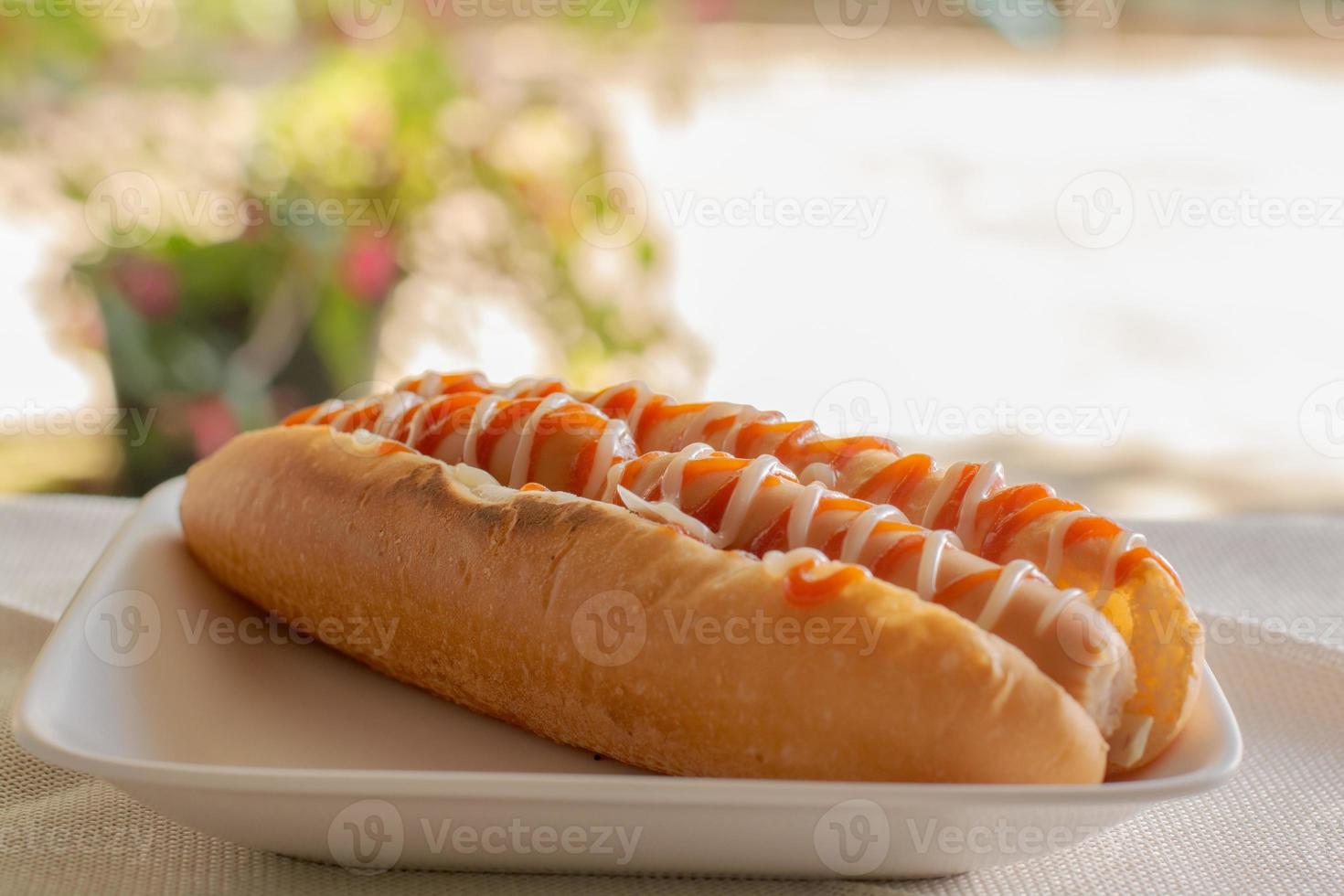 hot dog con pan y ketchup, mayonesa en plato blanco. sándwich de salchicha para el almuerzo. concepto de comida rápida. foto