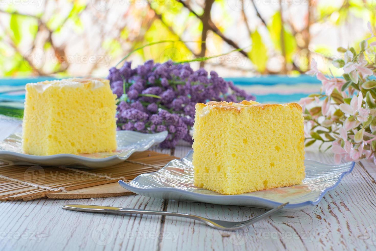 Piece of vanilla chiffon coconut cake on square plate on wooden table. Delicious small bakery for coffee and tea times. photo