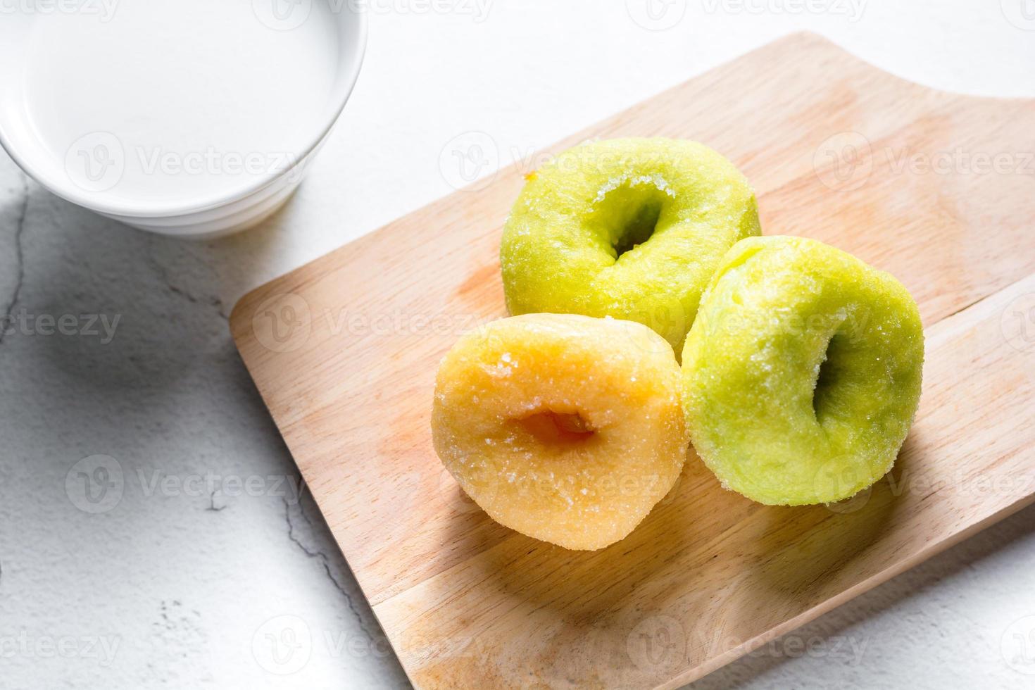 Vanilla and pandan doughnut on wooden chopping board with cup of hot milk. Breakfast concept. photo
