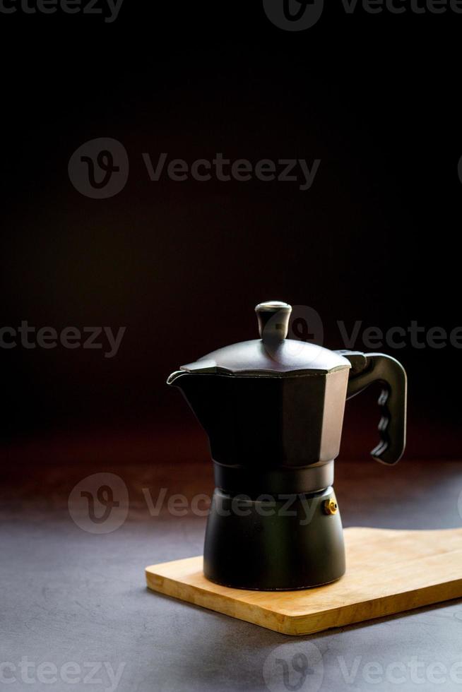 Espresso or black coffee and moka pot on wooden chopping board and dark table. Benefit of coffee concept. photo