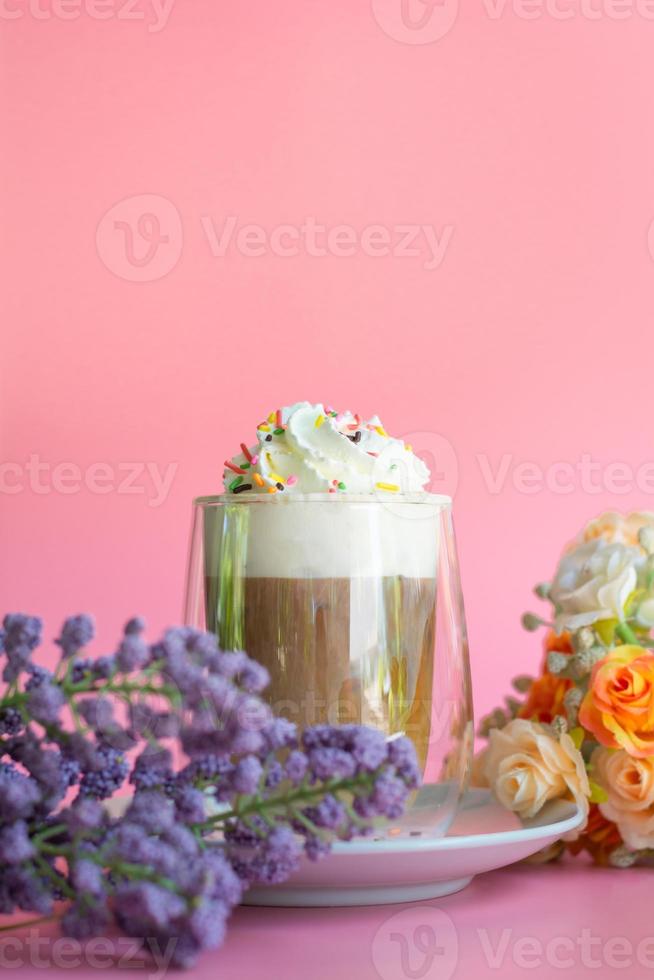 Ice coffee with a layer of milk and whipping cream with color sugar topping on pink background. Beverage and drink at the party concept. photo