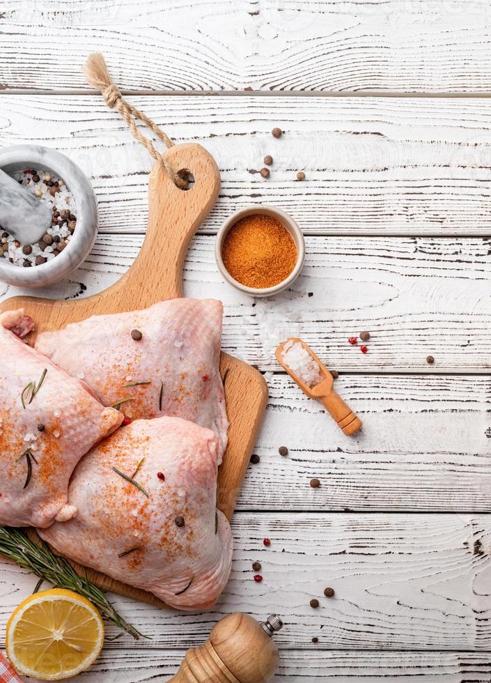 Sliced chicken thighs with skin on a cutting board. White wooden background. Top view. Copy space photo