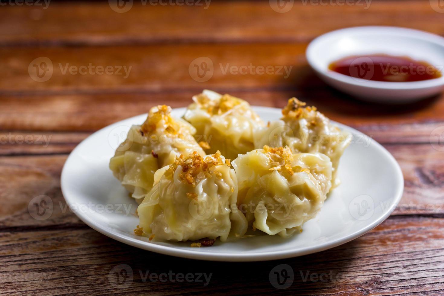 Chinese Steamed Dumpling, Shumai on white dish served with soy sauce on wooden table. Delicious Dimsum pork. photo