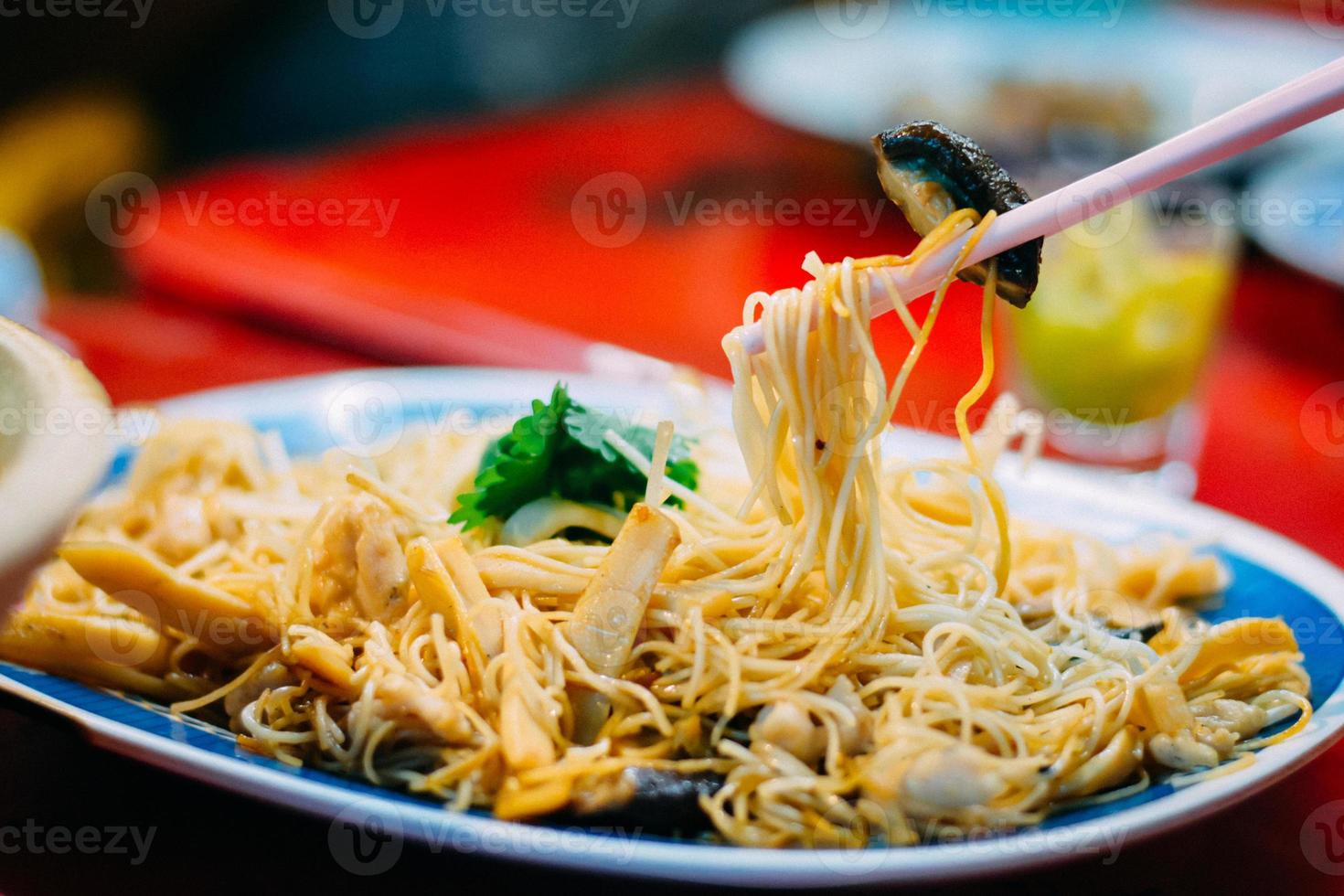 Delicious Chinese food. Eatting stir fried noodle and shiitake with chopsticks serve in restaurant at china town in Thailand. Selective focusing. photo