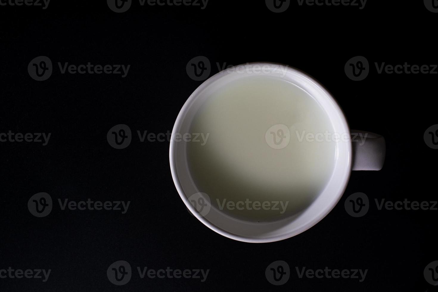 Top view of white cup of milk on black background with copy space. High protein and calcium. Healty beverage. photo