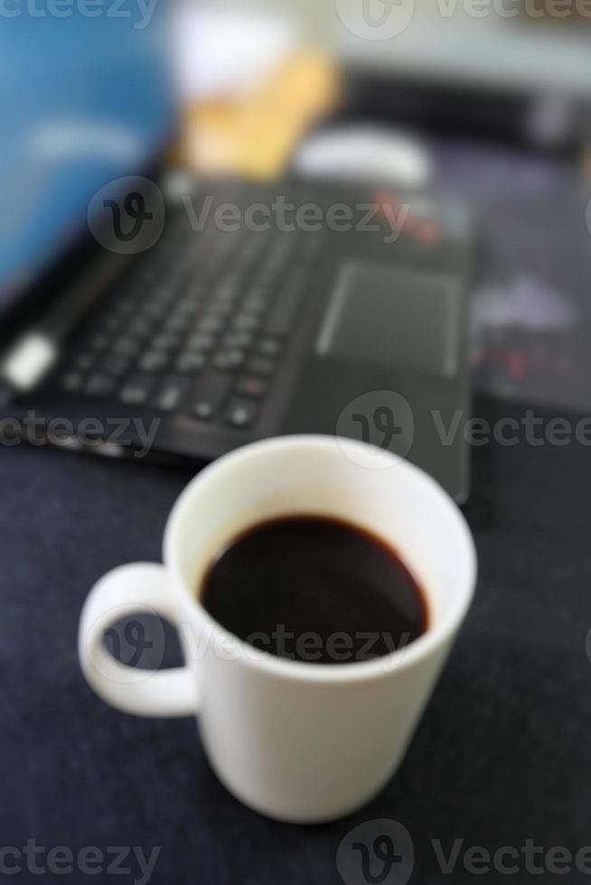 blur picture of coffee cup and part of computer keyboard on work table environment. business or financial or technology or working concept. photo