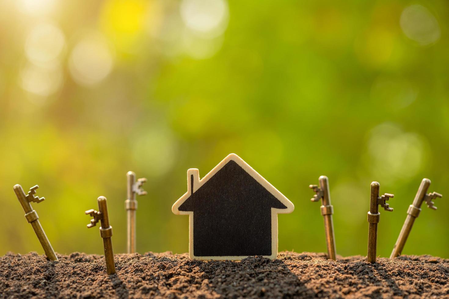 Wooden house growing in soil and vintage key on green nature blur background. Key to success about home business grow up concept photo