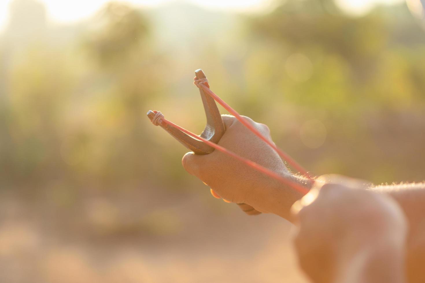 Man playing slingshot or catapult in morning time with sunlight effect photo