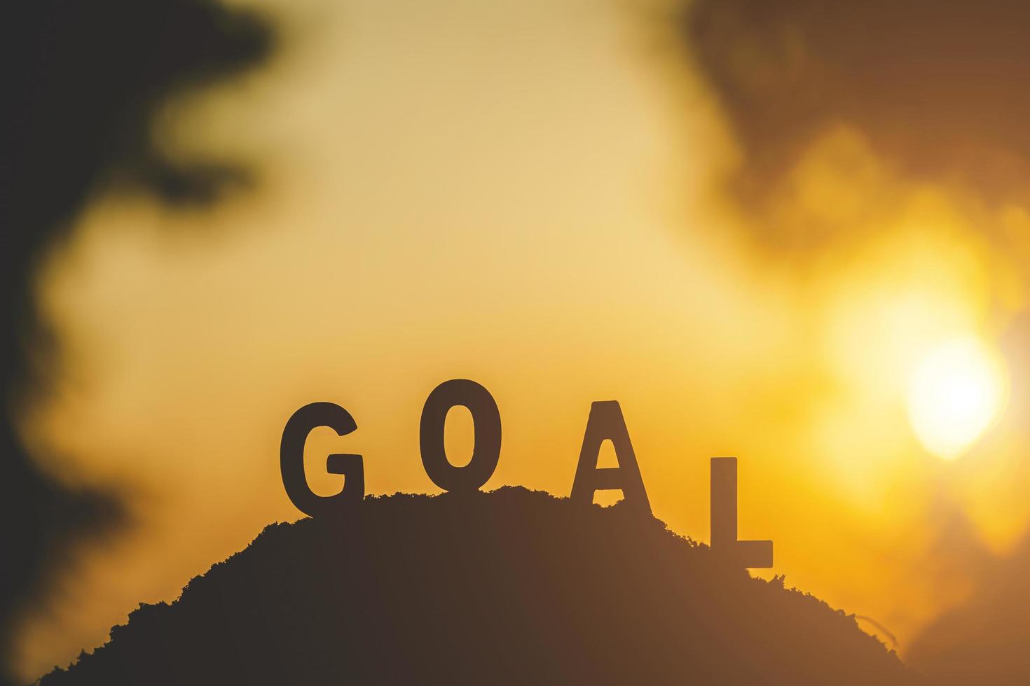 Silhouette of word GOAL on top of the hill in sunset time photo