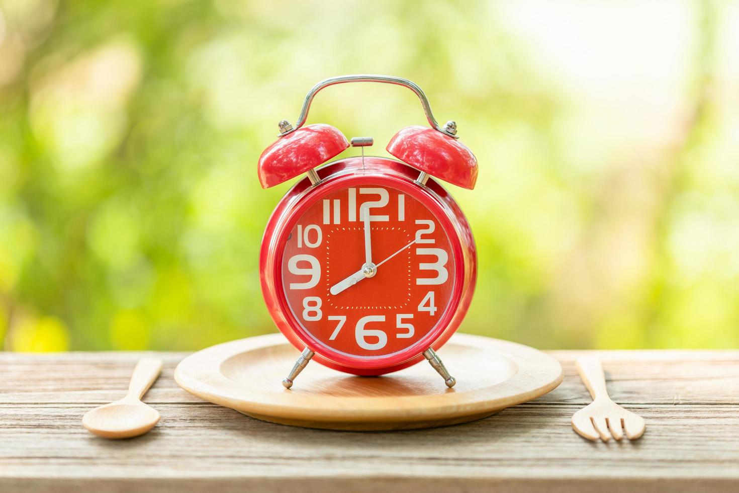 reloj despertador rojo tenedor y cuchara sobre una mesa de madera