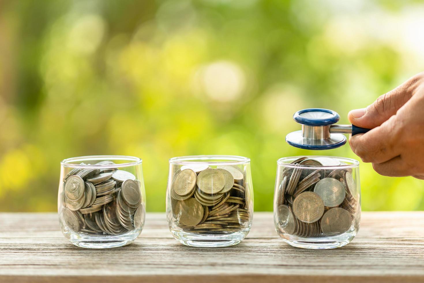 Blue stethoscope and jar of coin on wooden table. Money and financial checking concept photo