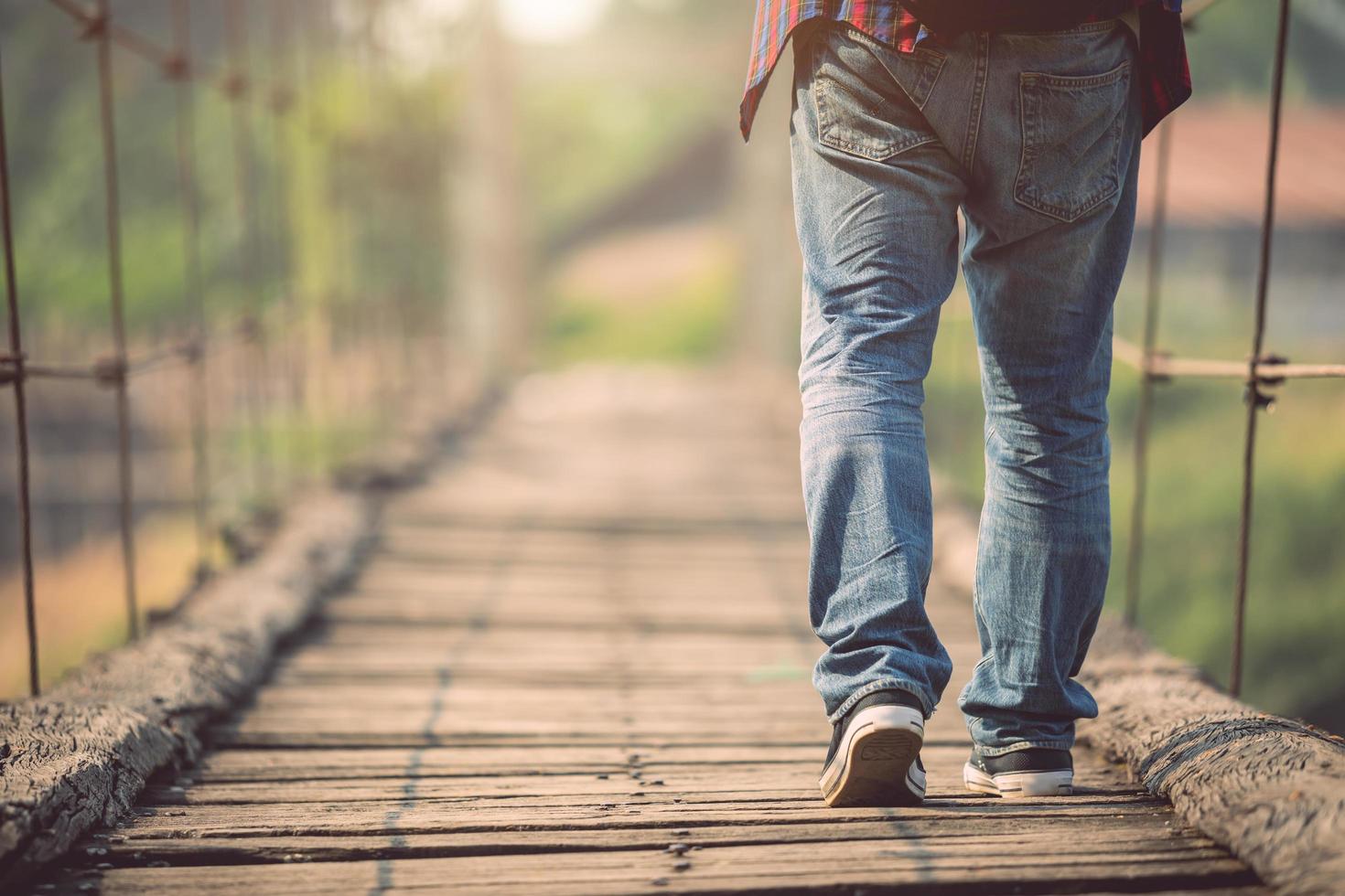 Asian tourist man walking on the old and broken wood bridge photo