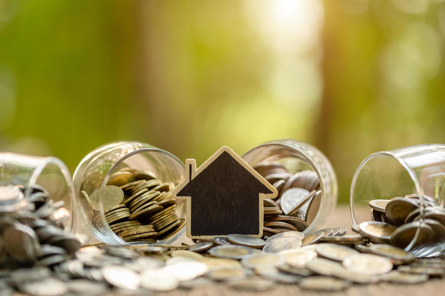 Wooden house model and coin stack on wooden table. Money savings for the home concept photo