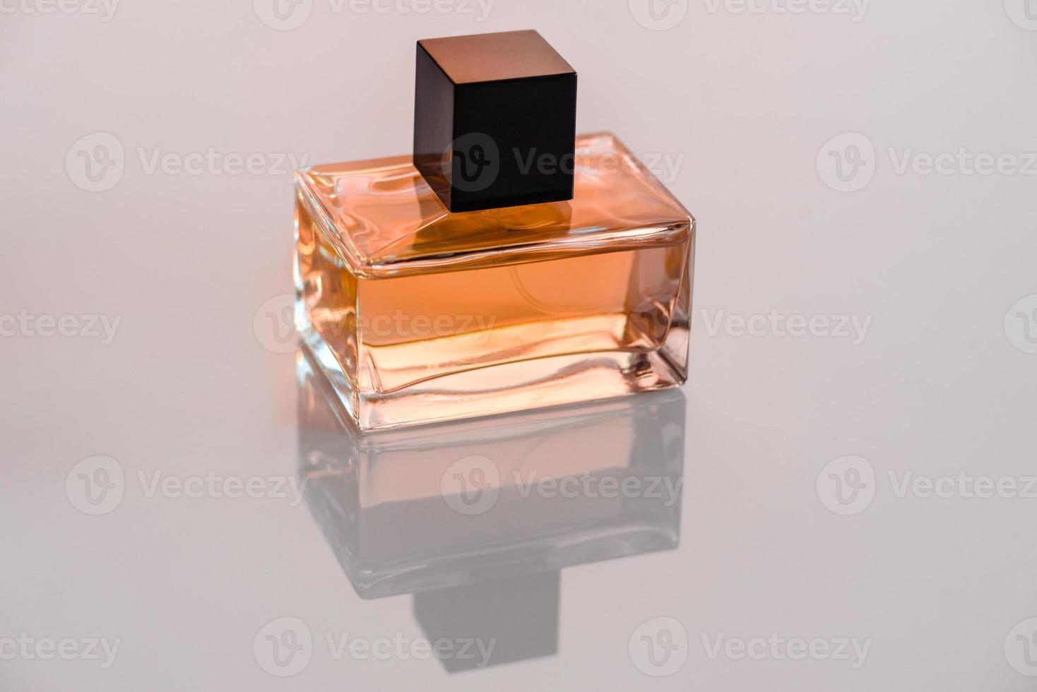 frasco de perfume de vidrio con una ramita de romero en un podio de madera foto