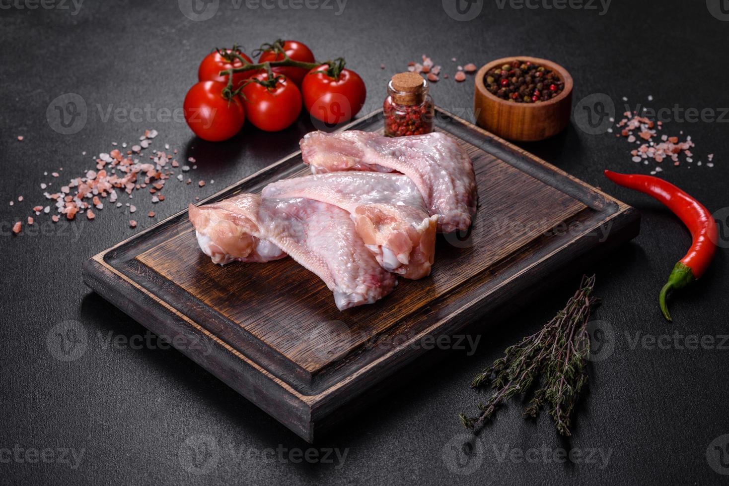 las alitas de pollo yacen sobre una tabla de madera sobre un fondo negro foto