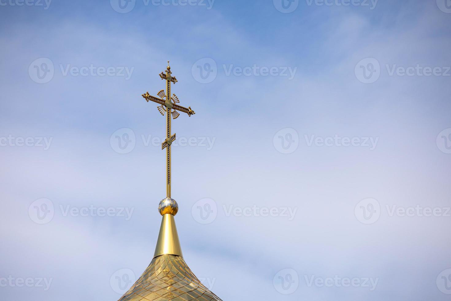 la cúpula dorada y la cruz de la iglesia ortodoxa contra el cielo azul y las nubes. foto