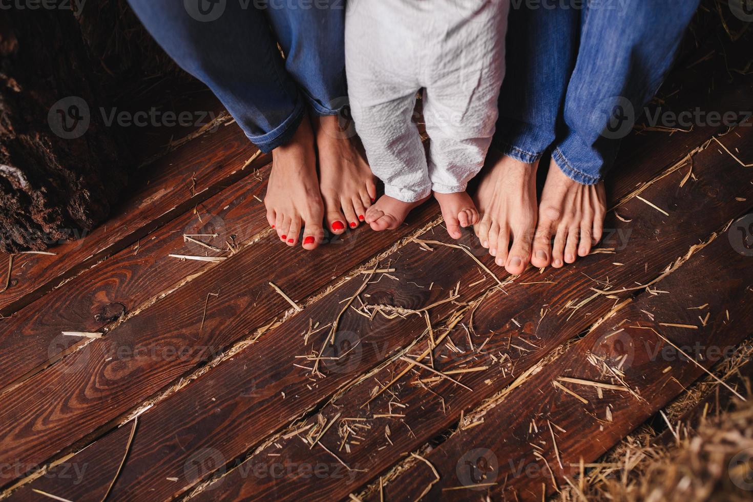 Bare feet of family members-mother, father and child. Wooden floor photo