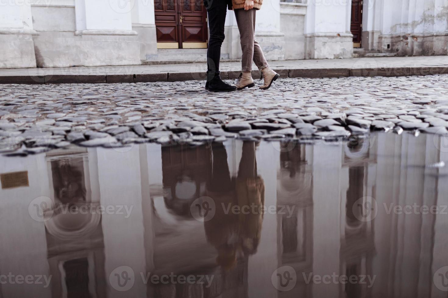 cropped photo of Happy young stylish couple, enjoying their hugging in old road in city street with ancient building on the background. after rain. selective focus