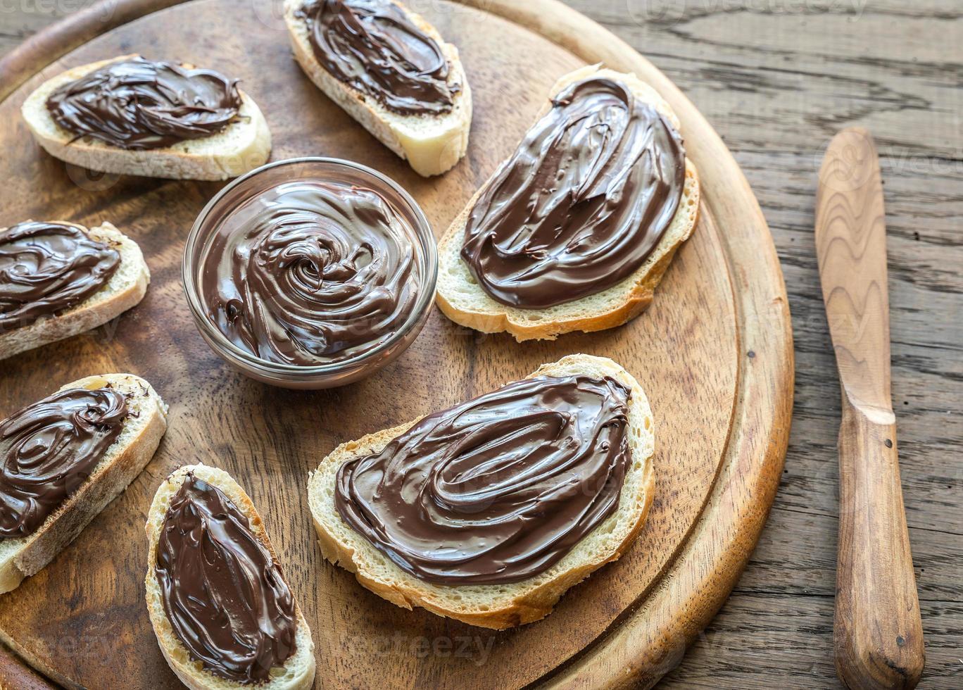 Slices of baguette with chocolate cream on the wooden board photo