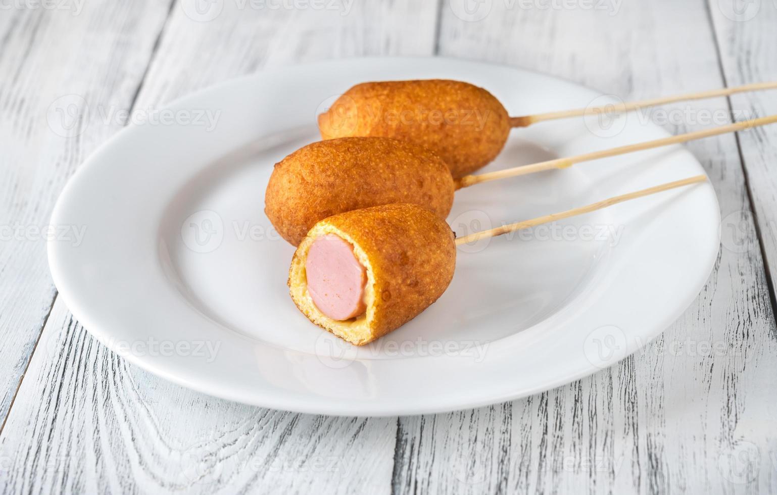 Corn dogs on white serving plate photo