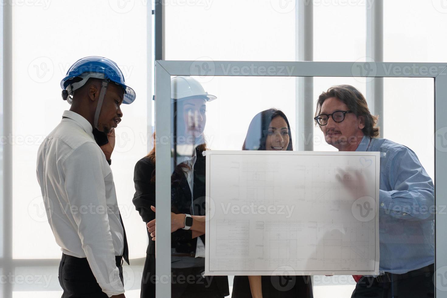 Senior Architect Presenting Blueprint of Building Project to Client Manager and Engineer inMeeting photo