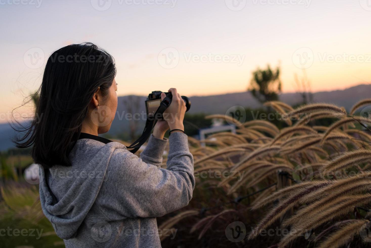 Mature Asian Woman Using Camera to Shoot Photos of Flowers at Sunset