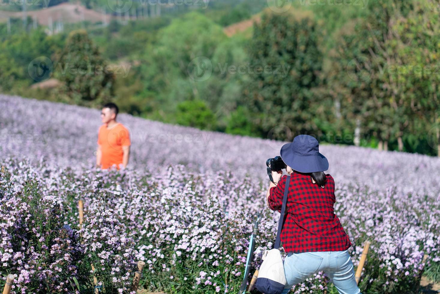 Woman taking photo of boyfriend in flowers garden