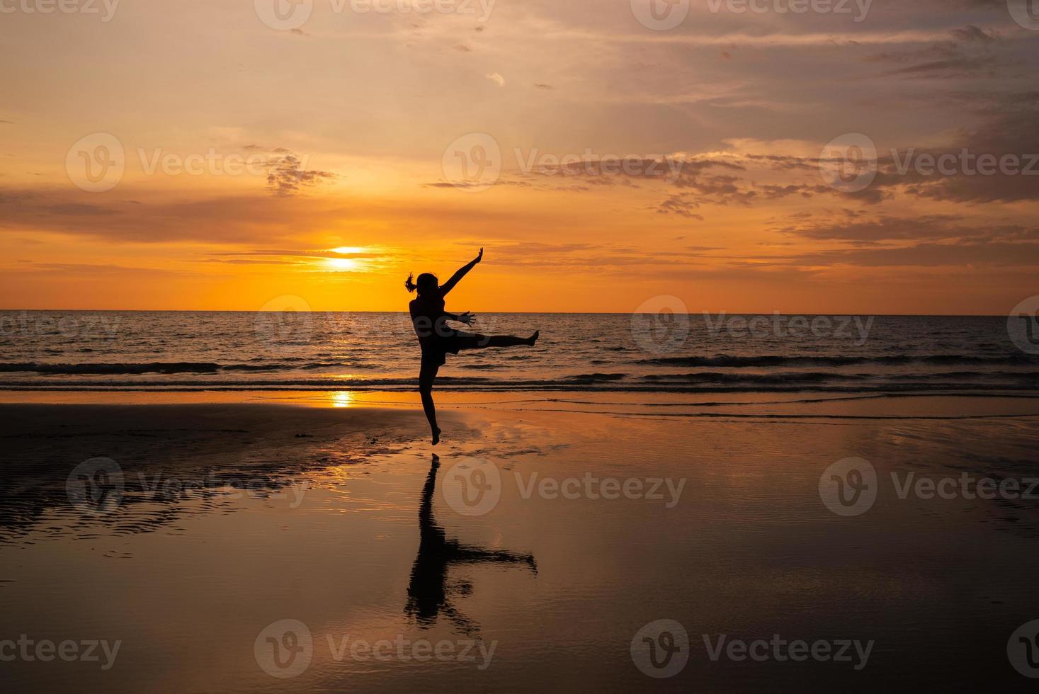Silhouette of Woman Jumping on Beach at Sunset photo