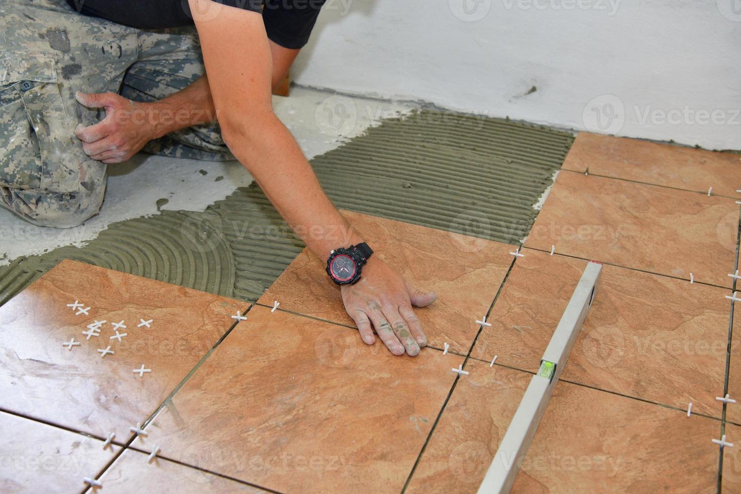 The mason on his knees lays tiles in the room 6046831 Stock Photo at
