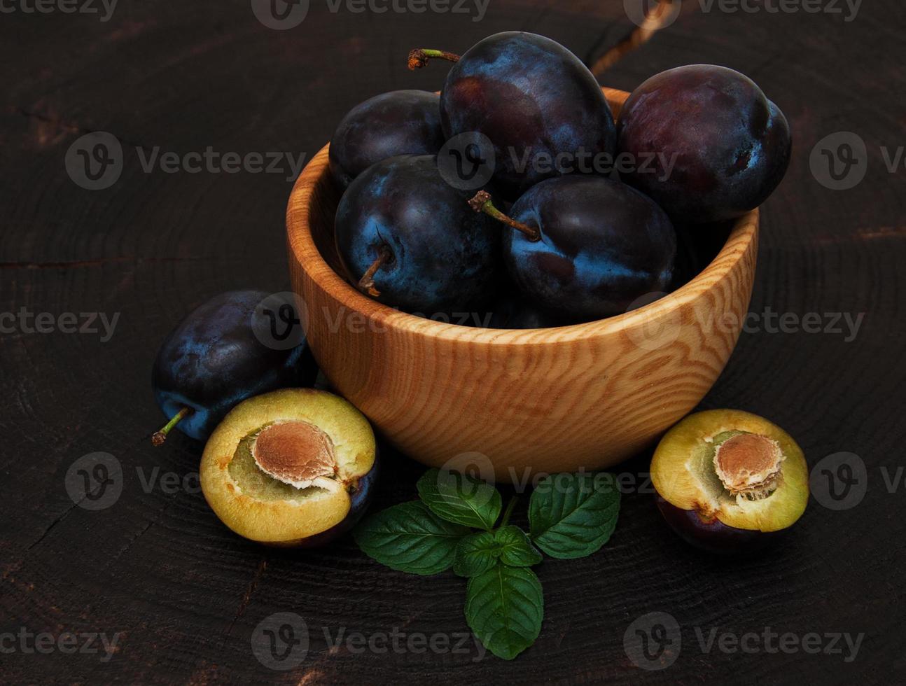 Bowl with  plums with green leaves photo