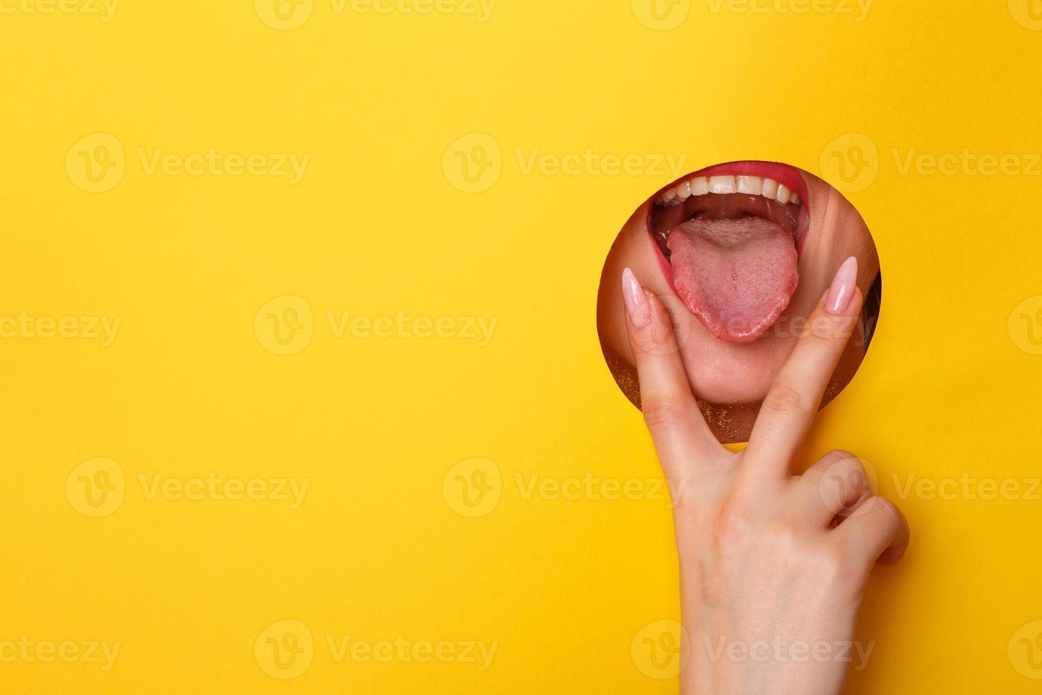 Woman looking in the hole, bright beautiful makeup, big eyes and lips, bright lipstick, professional cosmetics and facial care. Bright colored background and a gap slot in the paper photo