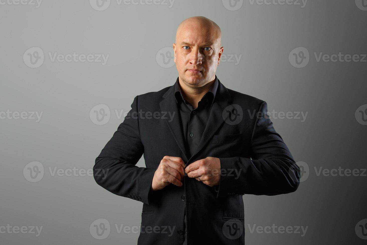 Adult cute bald man in a black suit and shirt posing on a gray background 6053724 Stock Photo at