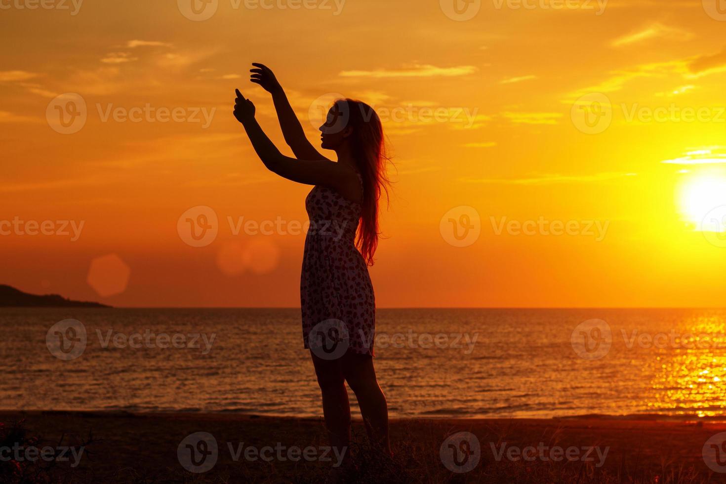 female silhouette at sunset on the beach, hands up photo
