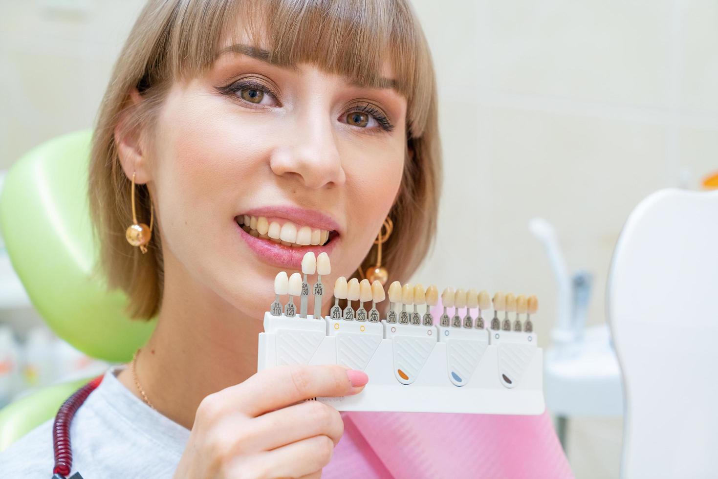 happy woman in dentistry picks up the color of tooth enamel photo