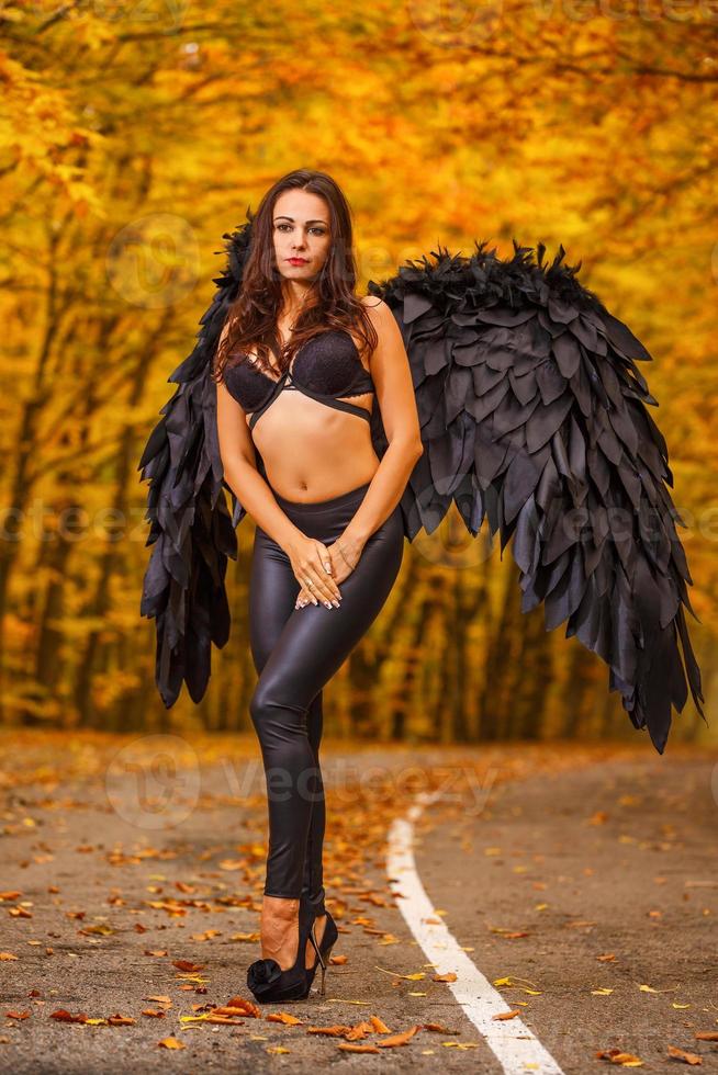 beautiful woman with black wings in autumn forest photo
