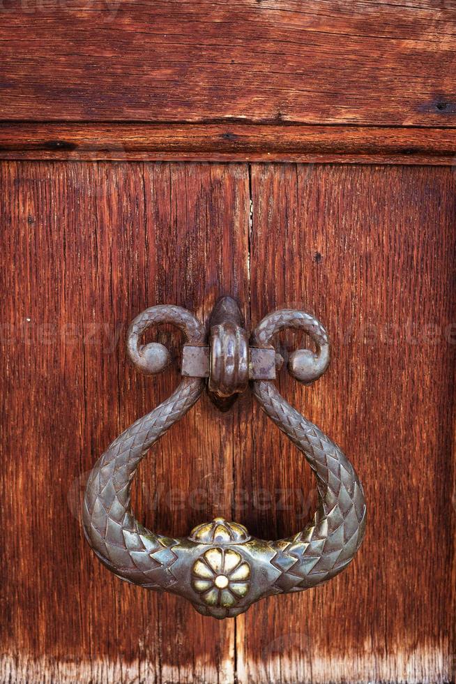 antique door knocker on dark wood background photo