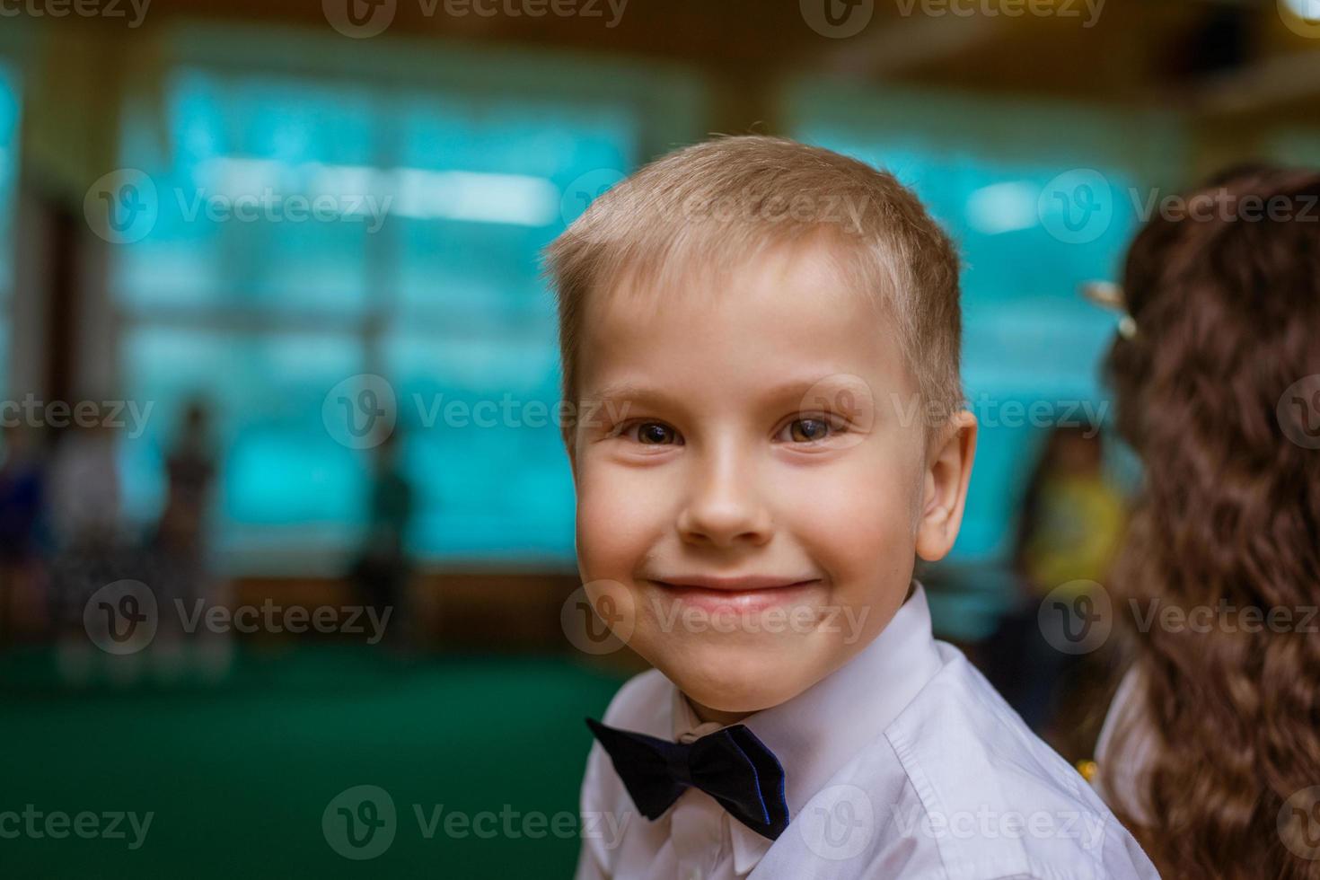 Portrait of a boy in white shirt and black bow tie, smiling cheerful schoolboy photo