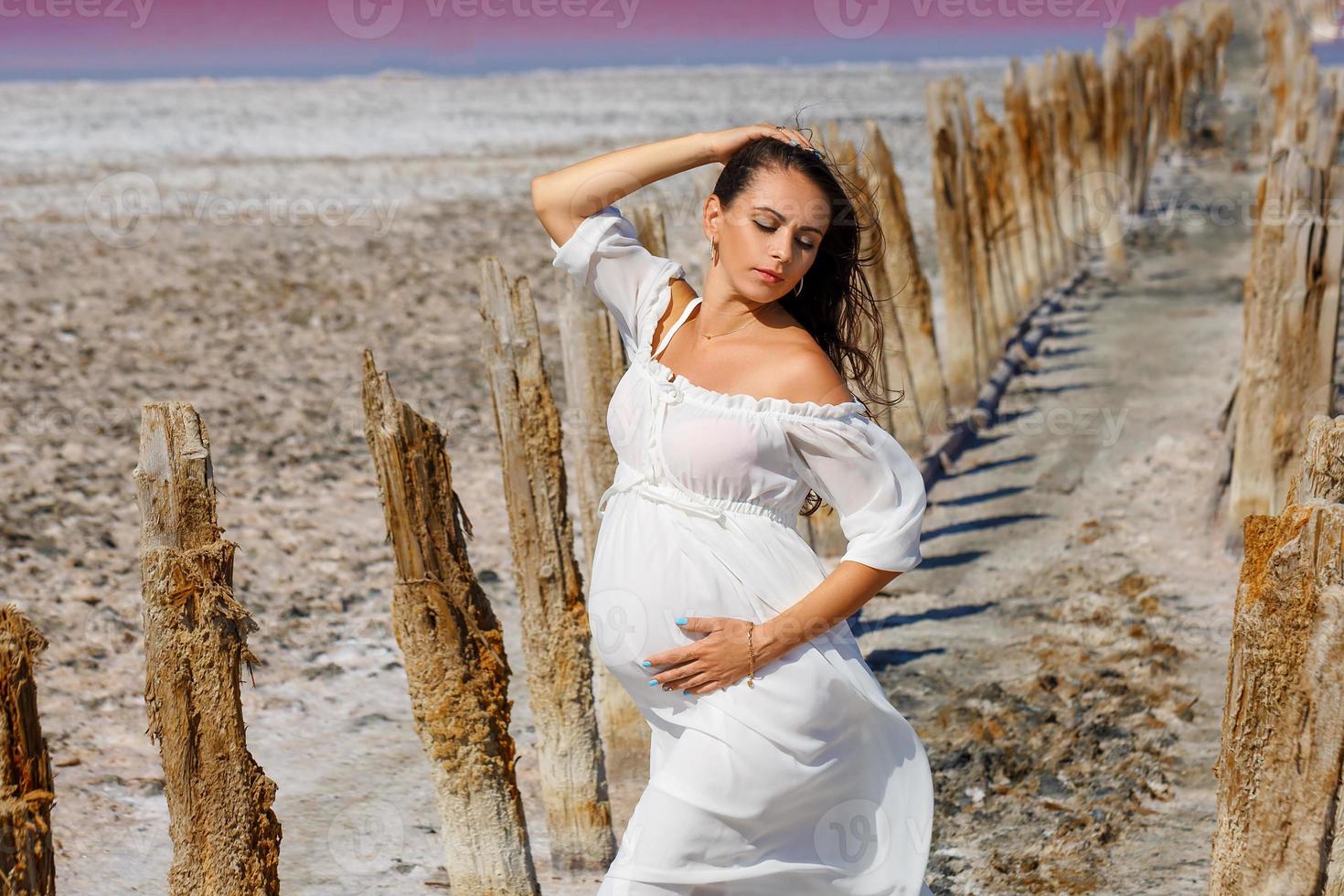 beautiful young pregnant woman standing in nature on salt lake photo