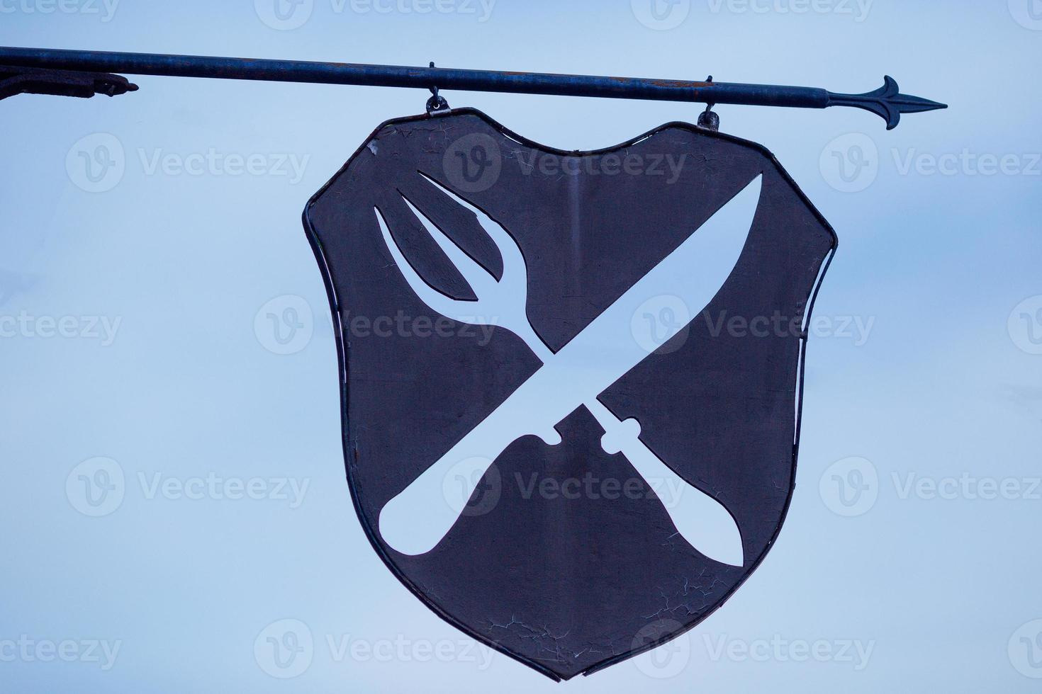 the iron sign of the cafe knife and fork crossed against the gloomy sky photo