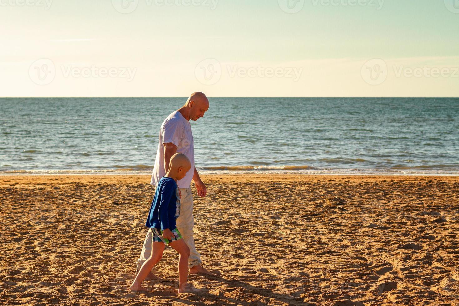 father and son walk along the beach at sunset, summer vacation family photo