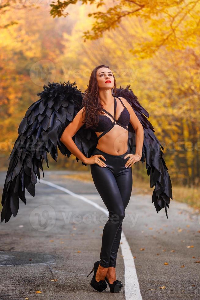 beautiful woman with black wings in autumn forest photo