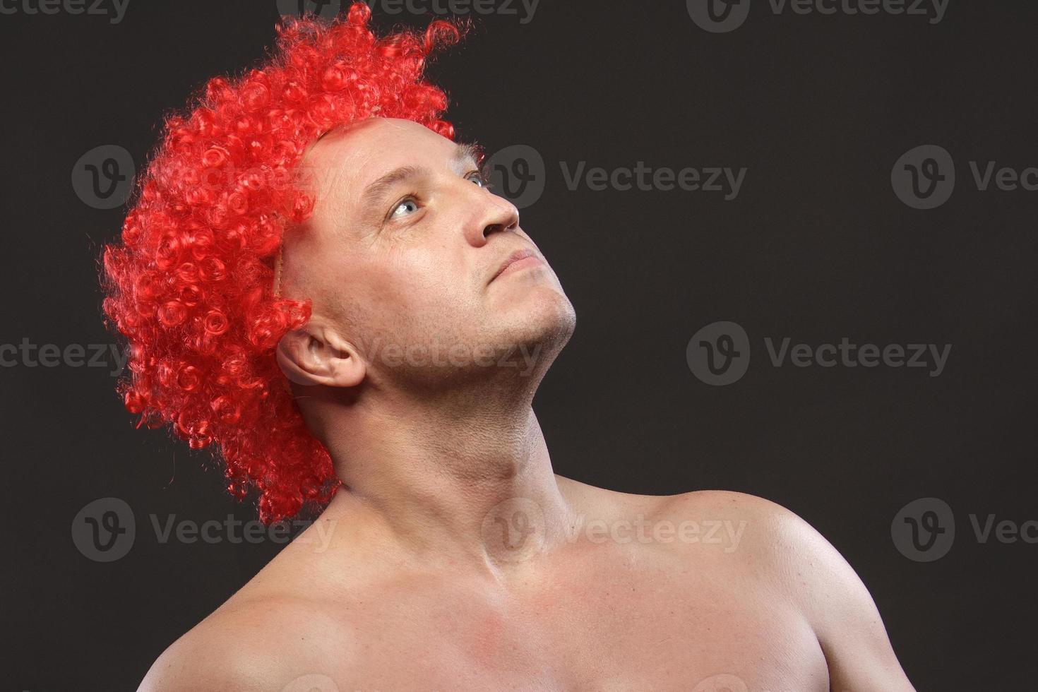 Portrait of a man in a bright red curly wig, funny facial expressions, on the background photo