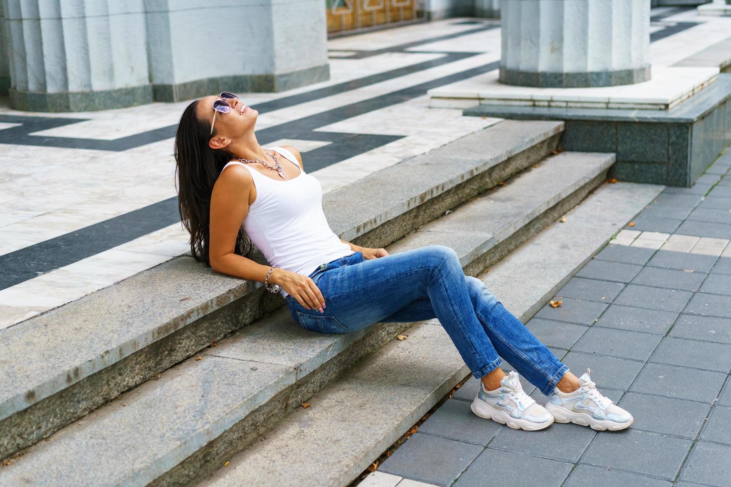 Casual style. Stylish woman in sunglasses sitting on a stone staircase. She was photo