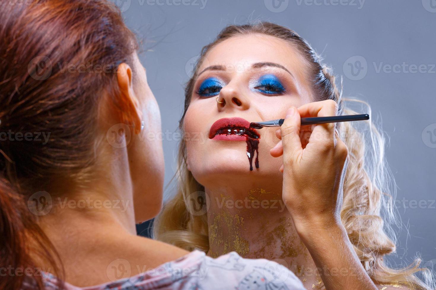 make up artist makes and applies makeup to the model photo