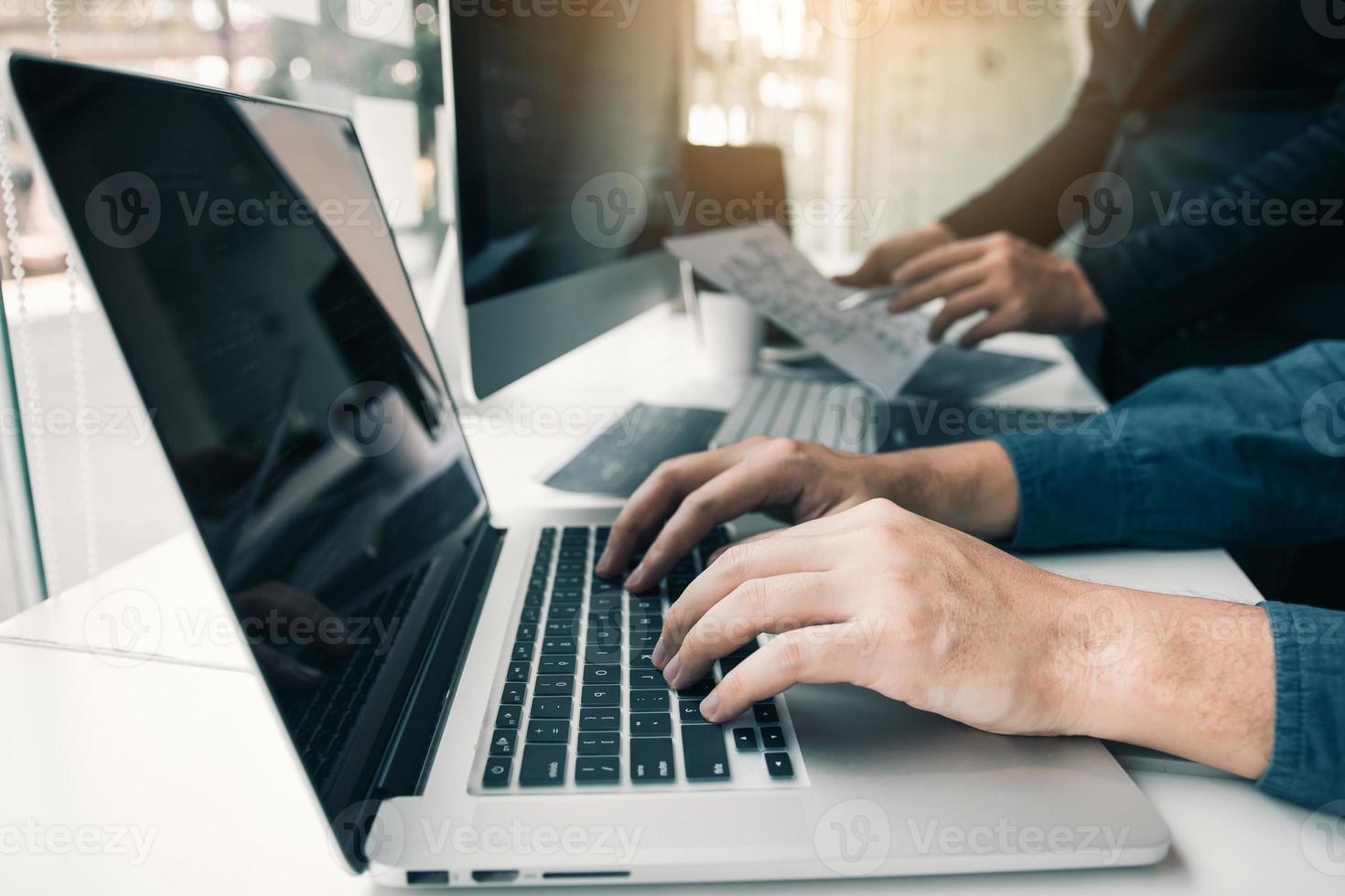 Two partnerships developing programming and coding technologies working on laptop and analyzing together. photo