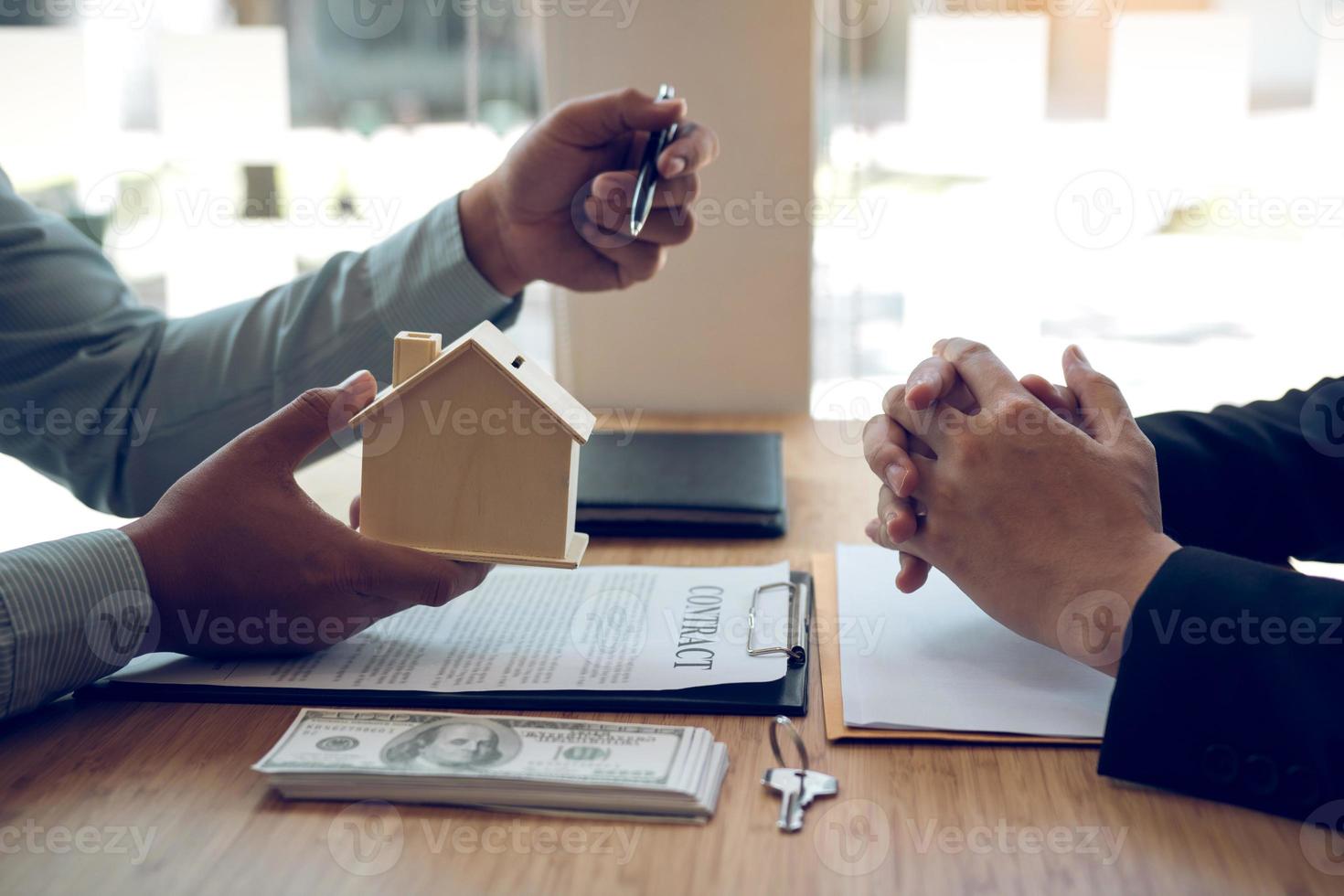 Business people home sales broker is using a pen pointing to the house model and describing the various components of the house. photo