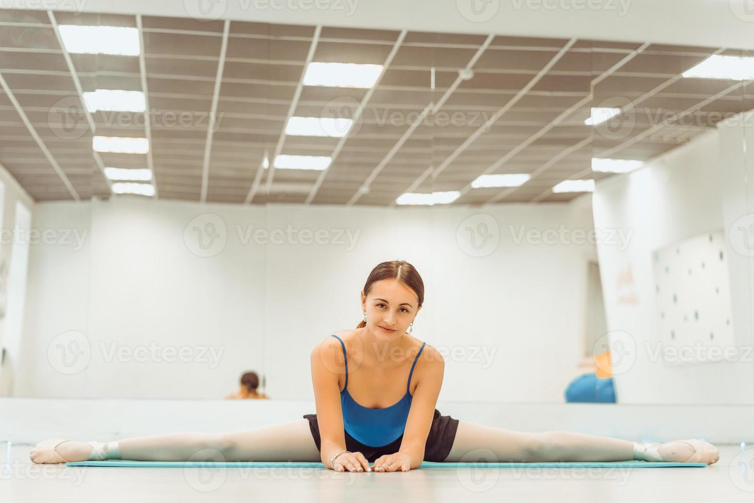 woman doing stretching on the Mat in the hall sitting on the twine photo