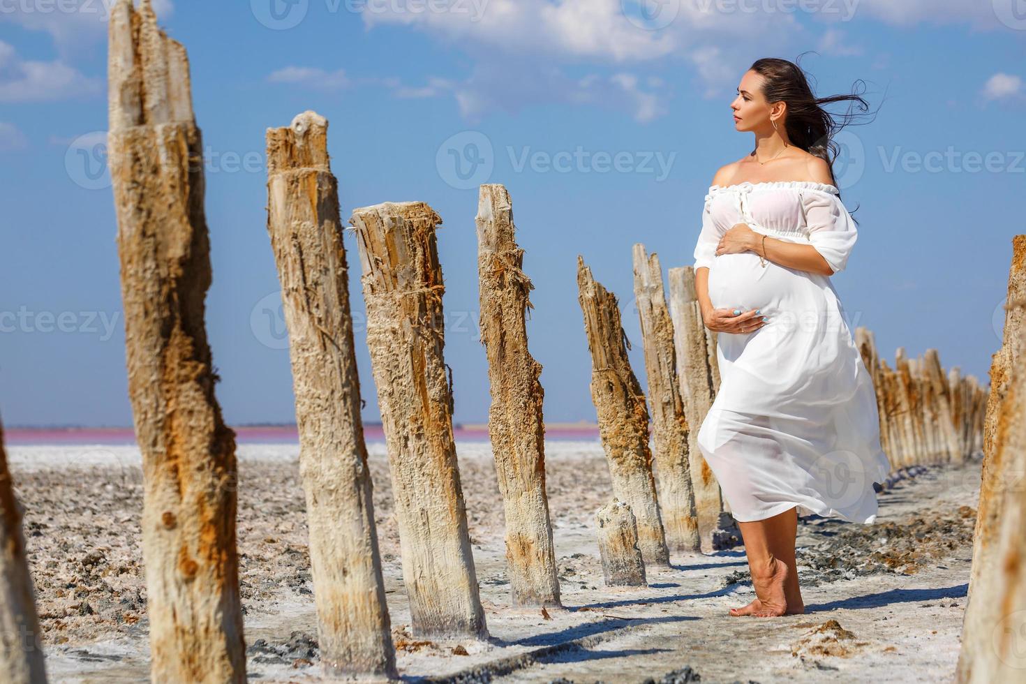 beautiful young pregnant woman standing in nature on salt lake photo