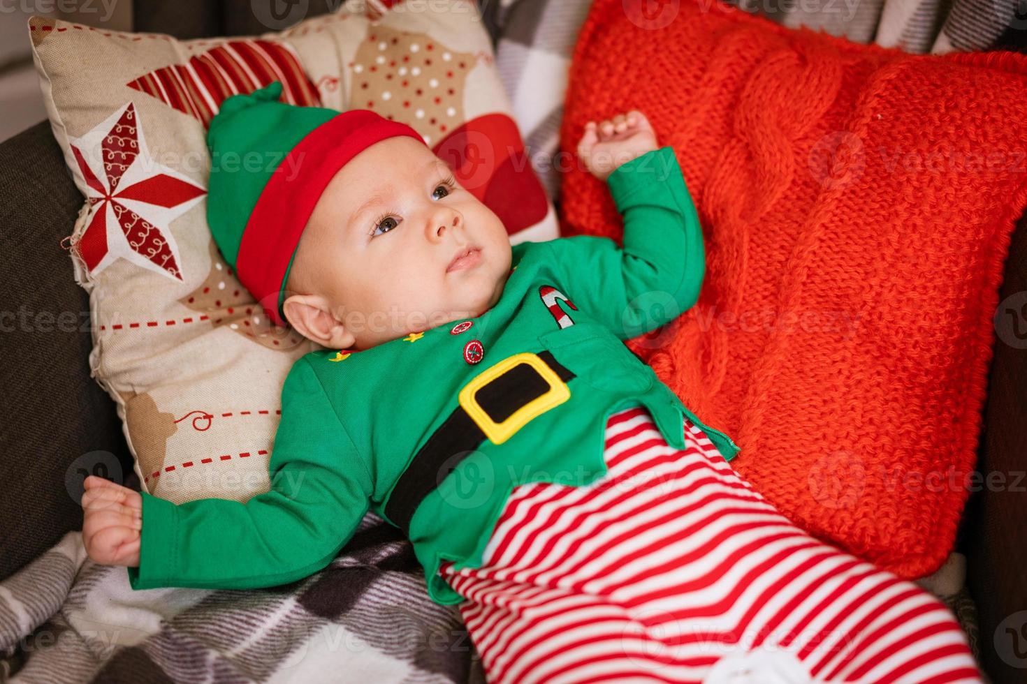 Christmas concept little boy cheerful elf looking up lies on multi-colored photo