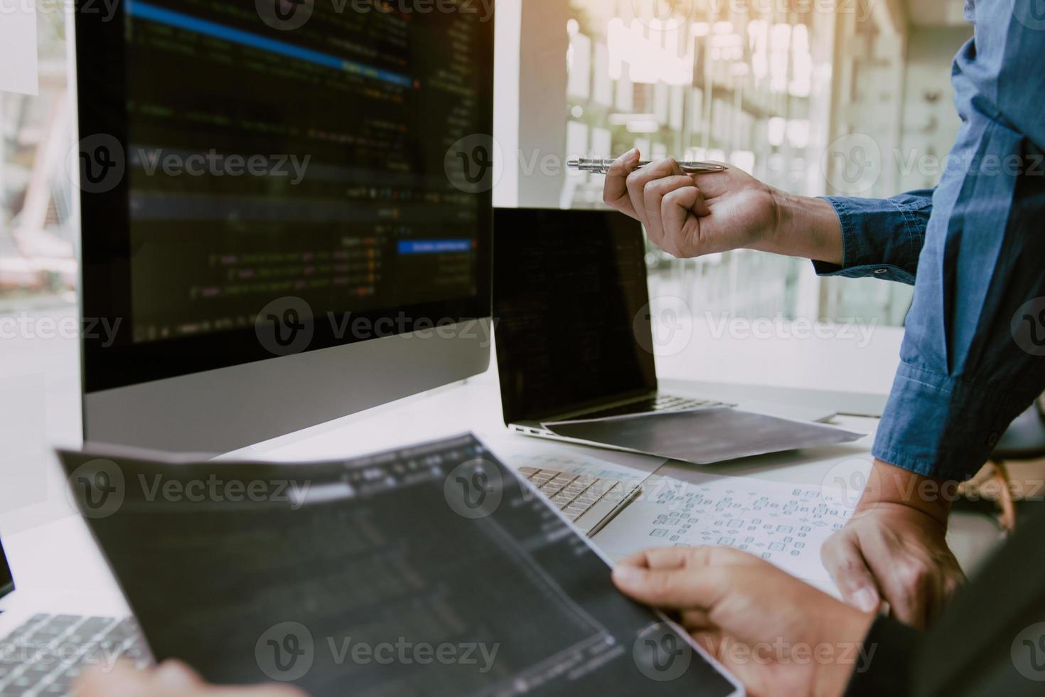 Two partnerships developing programming and coding technologies working on laptop and analyzing together. photo